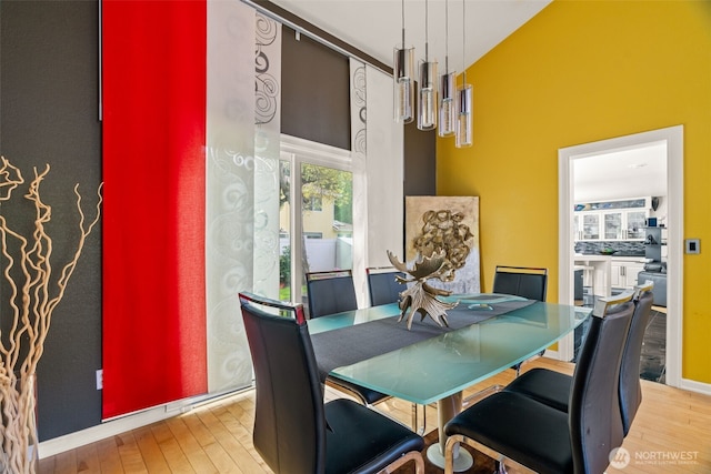 dining area featuring wood finished floors and a towering ceiling