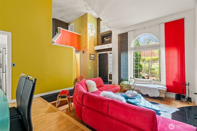 living room featuring wood-type flooring, a high ceiling, and baseboards
