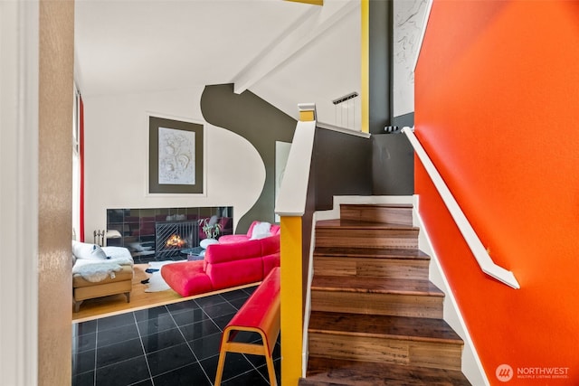 stairs with a tile fireplace and wood finished floors