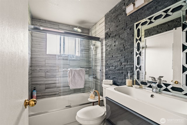 bathroom with toilet, combined bath / shower with glass door, and vanity
