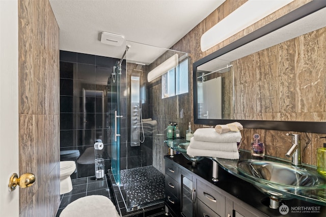 bathroom featuring toilet, tile walls, vanity, a shower stall, and tile patterned flooring