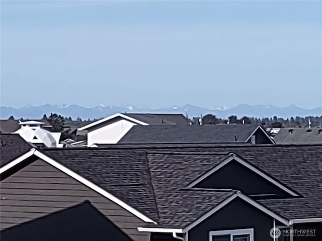 exterior view of roof with shingles and a mountain view