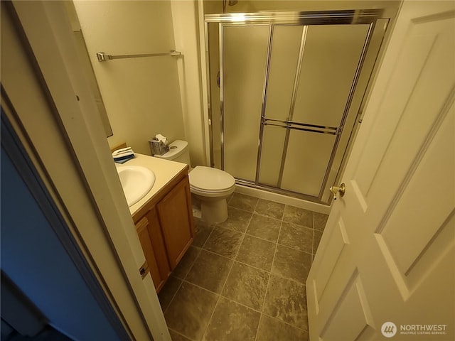 bathroom featuring toilet, a shower stall, and vanity