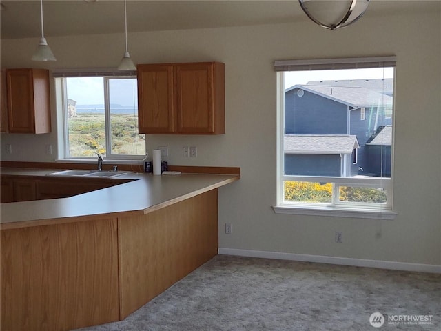 1400 Ocean Shores Blvd SW, Ocean Shores, WA 98569 - kitchen featuring light colored carpet, brown cabinets, pendant lighting, and light countertops