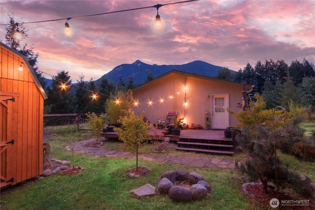 104 Jack Fir Ct, Packwood, WA 98361 - back of property at dusk with a deck with mountain view, a yard, and an outbuilding