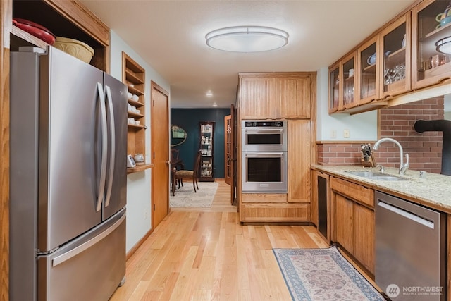 3246 Goshen Rd, Bellingham, WA 98226 - kitchen featuring appliances with stainless steel finishes, light wood-type flooring, light stone countertops, glass insert cabinets, and open shelves