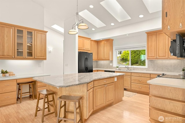 4415 Harborview Dr, Blaine, WA 98230 - kitchen with black appliances, a skylight, backsplash, light brown cabinetry, and light wood finished floors