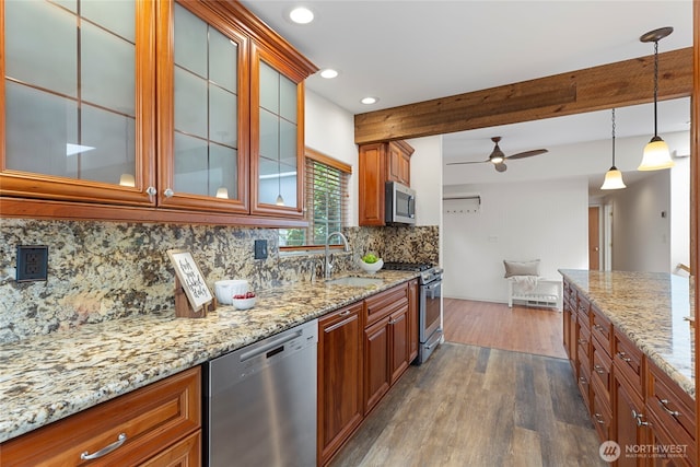 kitchen featuring appliances with stainless steel finishes, a sink, light stone countertops, backsplash, and recessed lighting