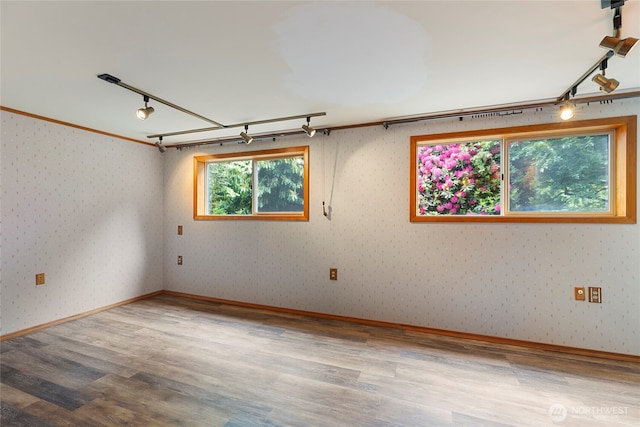 empty room with rail lighting, wood finished floors, and wallpapered walls
