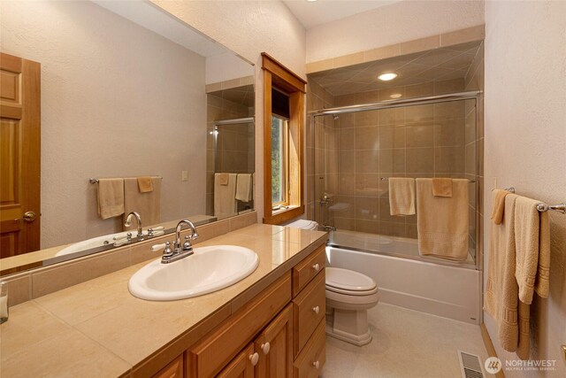 591 Wold Rd, Friday Harbor, WA 98250 - bathroom featuring toilet, a textured wall, vanity, and bath / shower combo with glass door