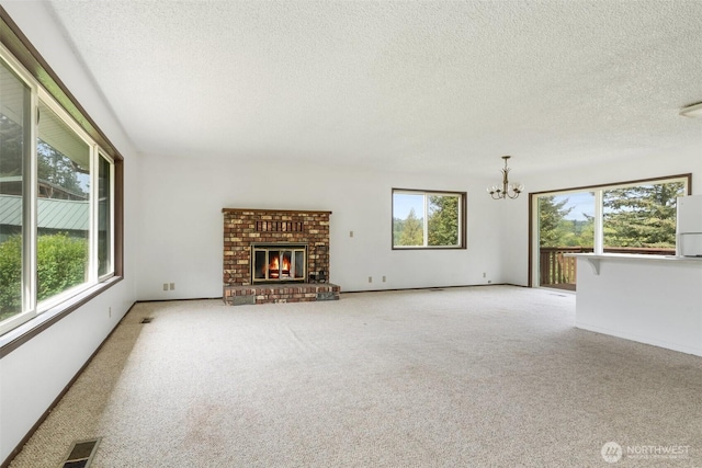 107 Mayfield Cir, Mossyrock, WA 98564 - unfurnished living room with a chandelier, plenty of natural light, a textured ceiling, carpet floors, and a fireplace