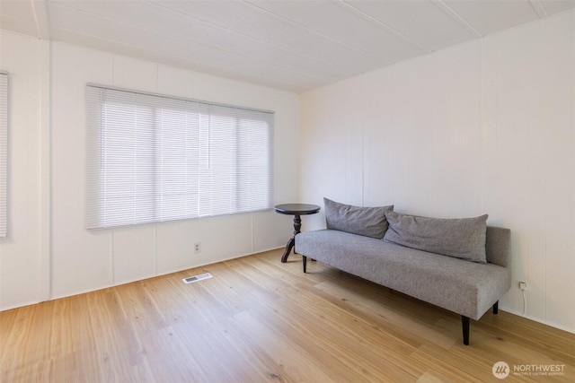 sitting room with wood finished floors and a decorative wall