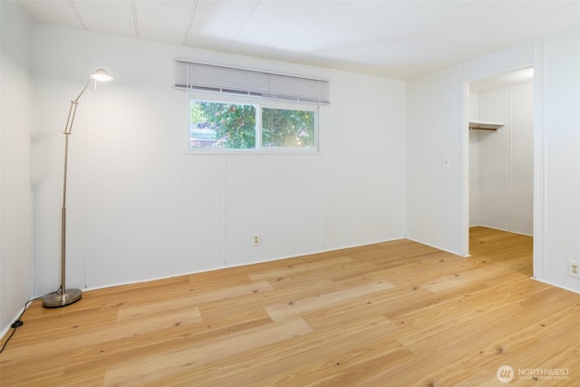 unfurnished bedroom with light wood-style flooring and a walk in closet