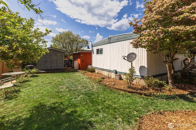 view of green lawn with a storage unit and an outbuilding