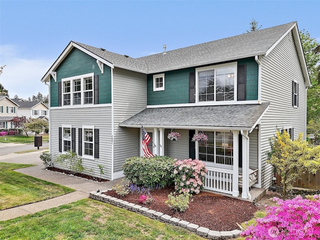 traditional-style home with roof with shingles and a porch