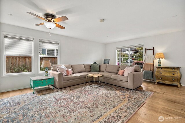 living area with light wood-style flooring, ceiling fan, and baseboards