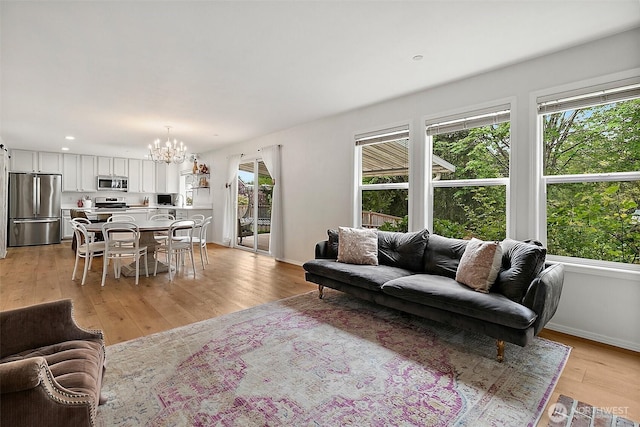 living room with plenty of natural light, a chandelier, light wood-type flooring, baseboards, and recessed lighting
