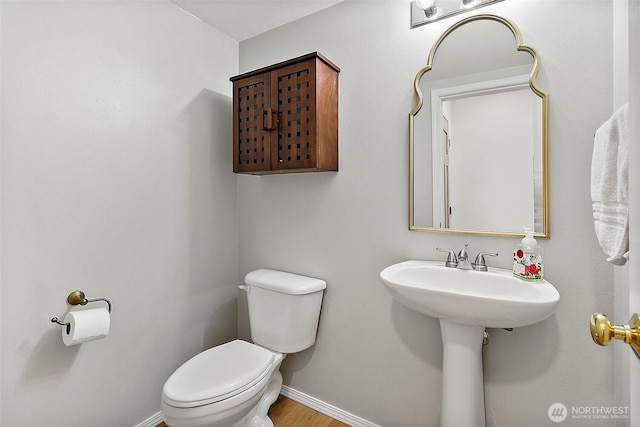 bathroom featuring toilet, baseboards, and wood finished floors