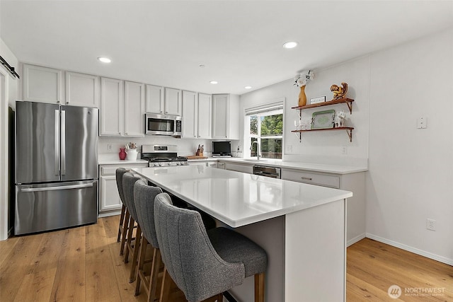 kitchen with stainless steel appliances, light wood-style flooring, light countertops, a breakfast bar, and recessed lighting