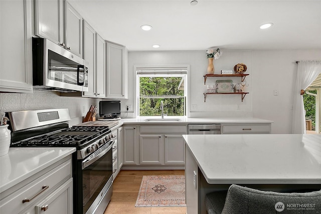 kitchen featuring stainless steel appliances, a sink, plenty of natural light, light countertops, and recessed lighting