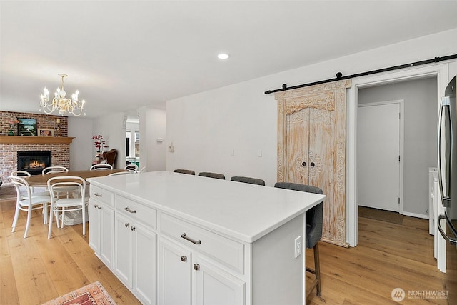kitchen with light wood-style flooring, open floor plan, a barn door, a fireplace, and recessed lighting