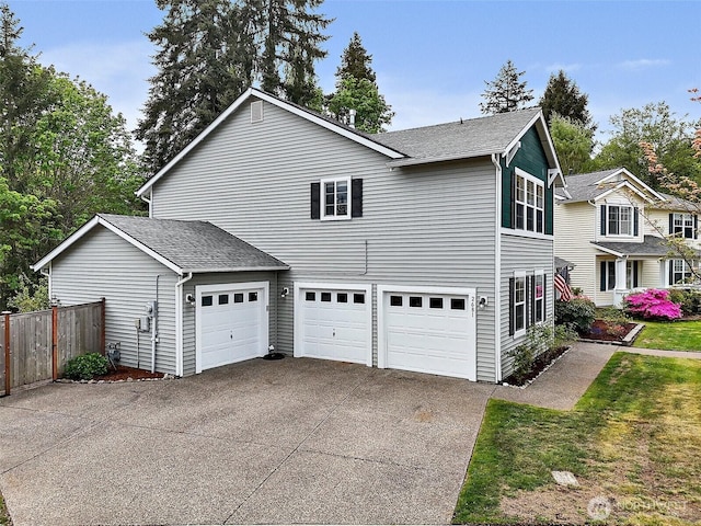 view of home's exterior featuring concrete driveway, fence, an attached garage, and a shingled roof