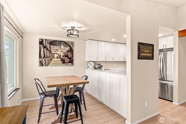 dining area featuring light wood-type flooring and baseboards
