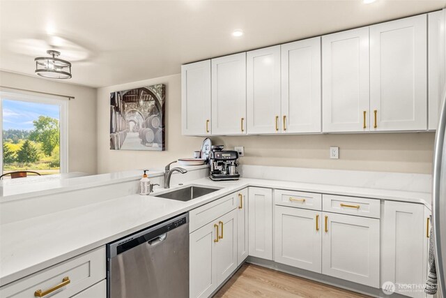 kitchen featuring stainless steel dishwasher, a sink, light countertops, white cabinets, and recessed lighting
