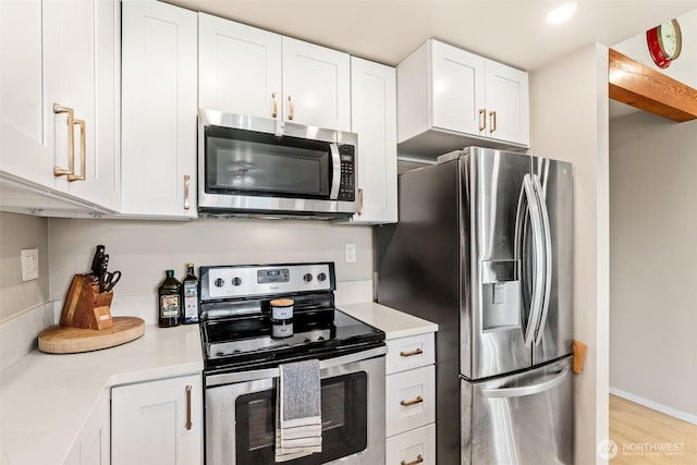 kitchen with appliances with stainless steel finishes, light countertops, white cabinetry, and light wood finished floors