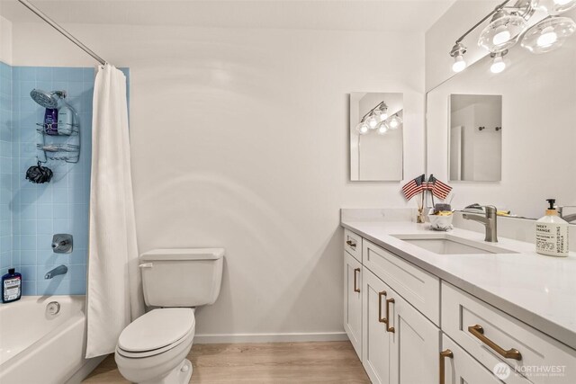 bathroom with toilet, vanity, shower / bath combo with shower curtain, wood finished floors, and baseboards
