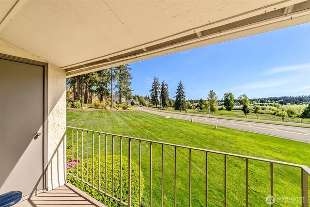 view of green lawn featuring a balcony