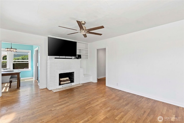 unfurnished living room with a fireplace, ceiling fan, light wood-style flooring, and baseboards