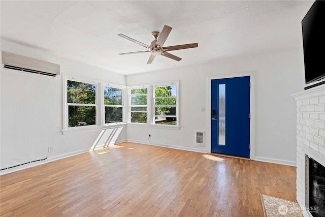 unfurnished living room featuring a wall mounted air conditioner, a fireplace, ceiling fan, wood finished floors, and baseboards