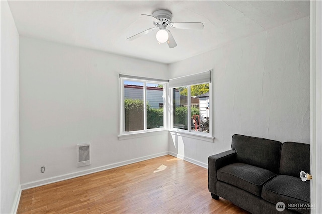 living area featuring wood finished floors, baseboards, and a ceiling fan