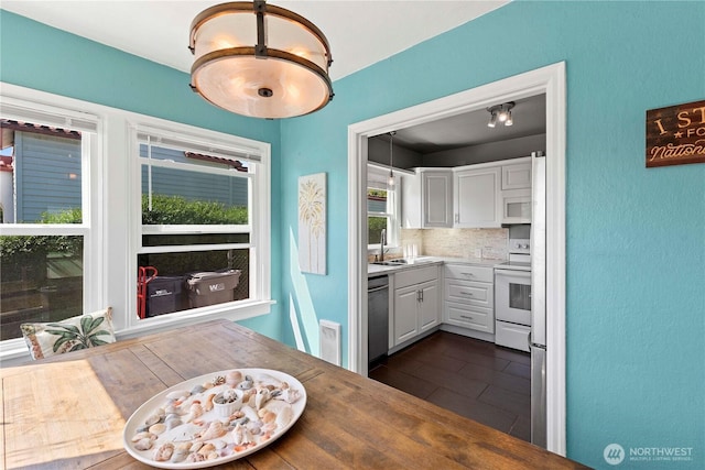 kitchen with white appliances, white cabinets, backsplash, a textured wall, and a sink