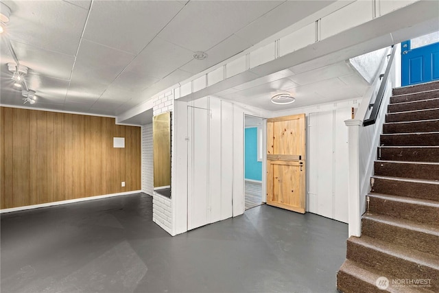 finished below grade area featuring stairs and wooden walls