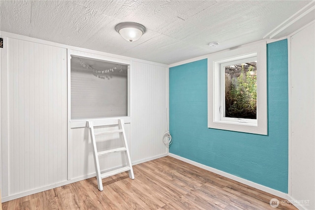 unfurnished bedroom with wood finished floors, baseboards, and a textured ceiling