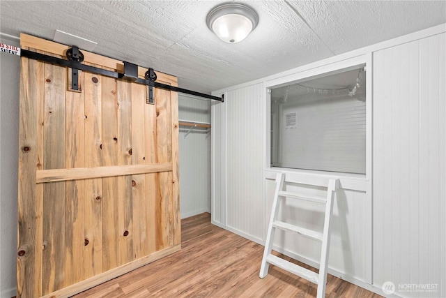 unfurnished bedroom featuring wood finished floors and a barn door