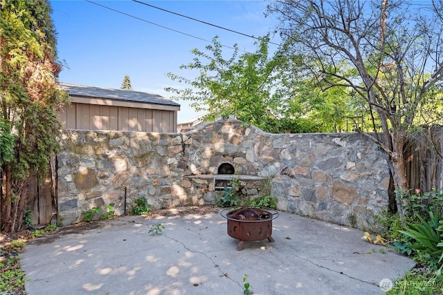 view of patio / terrace with exterior fireplace, an outdoor fire pit, and fence