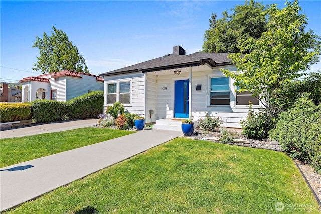 bungalow-style home featuring a front yard and a chimney