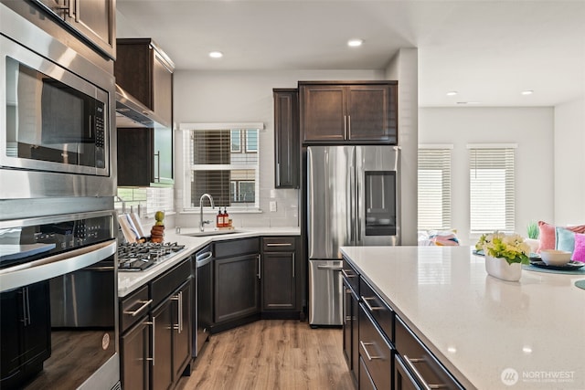 207 207th St SE Unit Eh49, Bothell, WA 98012 - kitchen with stainless steel appliances, a sink, light wood-type flooring, backsplash, and dark brown cabinetry