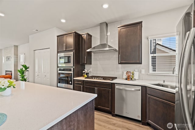 207 207th St SE Unit Eh49, Bothell, WA 98012 - kitchen with appliances with stainless steel finishes, wall chimney range hood, backsplash, dark brown cabinetry, and light wood-style flooring