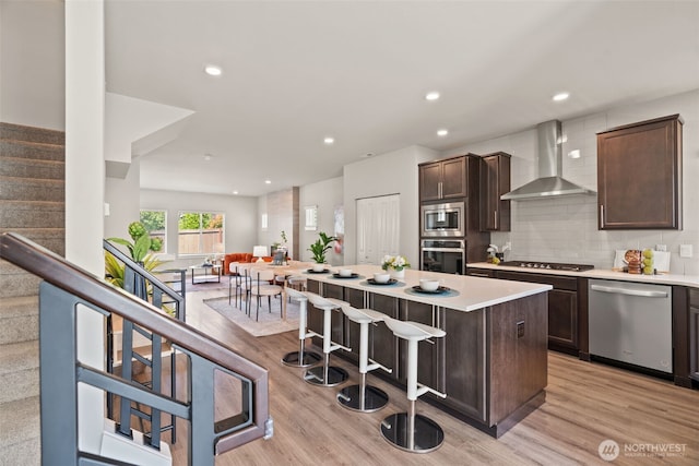 207 207th St SE Unit Eh49, Bothell, WA 98012 - kitchen featuring appliances with stainless steel finishes, wall chimney range hood, a center island, dark brown cabinets, and a kitchen bar