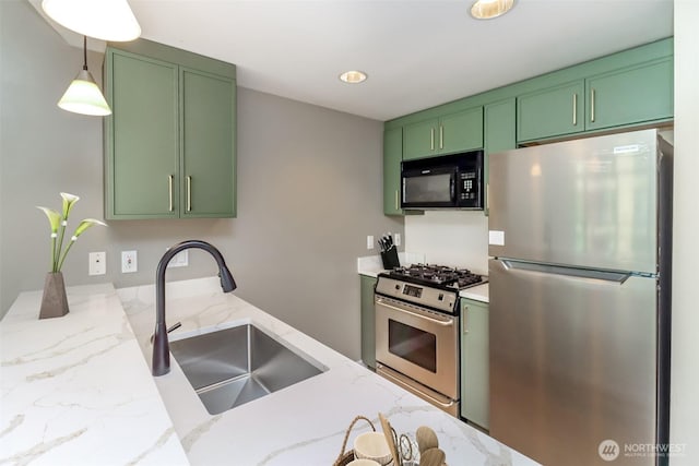 kitchen with appliances with stainless steel finishes, green cabinets, a sink, and light stone countertops