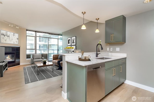 kitchen featuring dishwasher, a sink, light countertops, light wood-style floors, and a peninsula