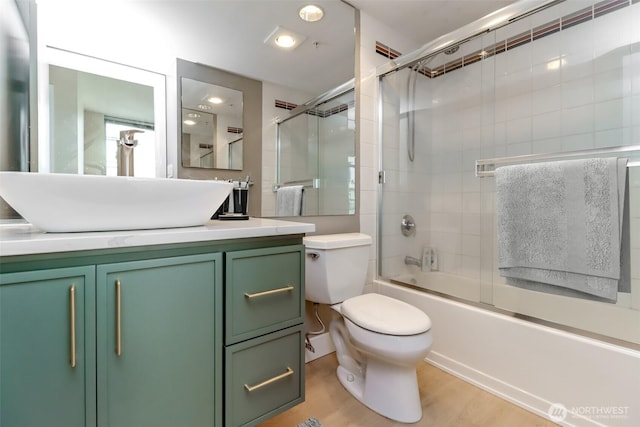 full bathroom with combined bath / shower with glass door, vanity, toilet, wood finished floors, and recessed lighting