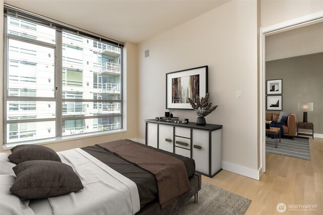 bedroom with light wood-style floors, multiple windows, and baseboards