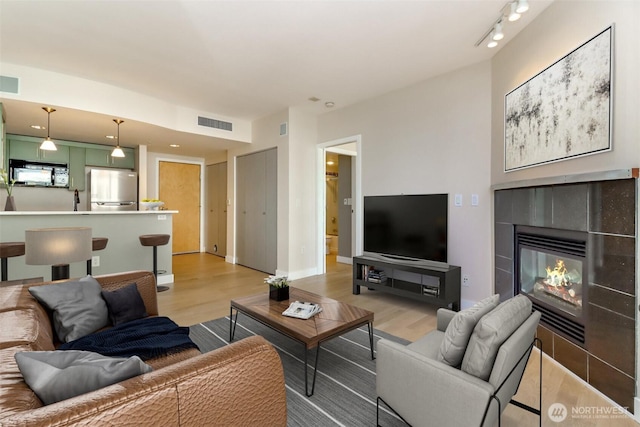 living area with light wood-type flooring and a tile fireplace