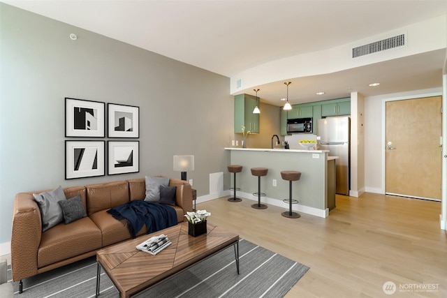 living room with light wood-style floors, recessed lighting, and baseboards