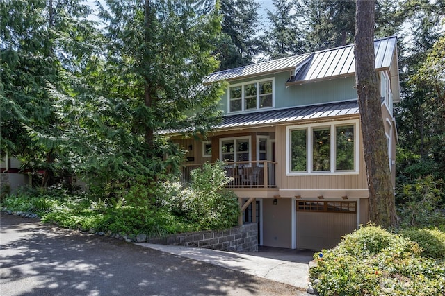 view of front of home with a standing seam roof, an attached garage, driveway, and metal roof
